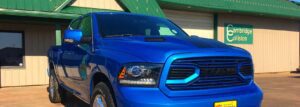 A large blue truck, photo focusing on the front grill and headlights.