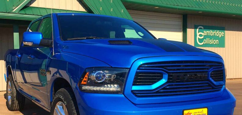 A large blue truck, photo focusing on the front grill and headlights.
